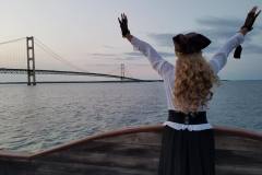 Good-Fortune-pirate-lady-with-arms-raised-in-front-of-Mackinac-Bridge